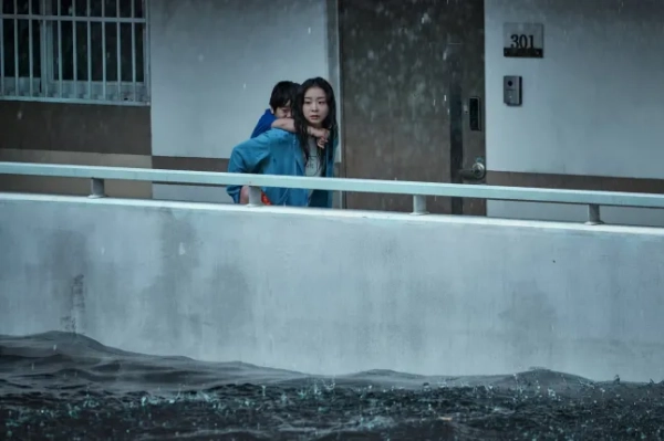 Кім Да-мі в ролі Гу Ан-на несе хлопчика на спині під дощем, поки рівень води піднімається у фільмі 