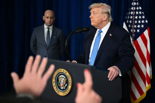 (Л/П) Заступник начальника апарату Стівен Міллер спостерігає за тим, як президент США Дональд Трамп виступає перед пресою після військових дій США у Венесуелі у своїй резиденції Мар-а-Лаго в Палм-Біч, Флорида, 3 січня 2026 року. Президент Трамп заявив у суботу, що американські війська захопили лідера Венесуели Ніколаса Мадуро після «широкомасштабного удару» по цій південноамериканській країні. (Фото Джима ВОТСОН / AFP via Getty Images)