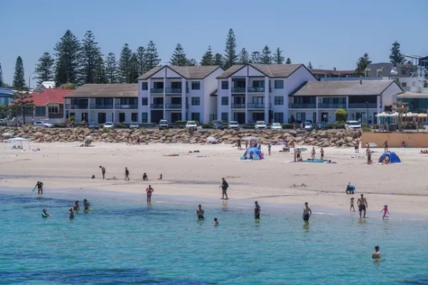 Люди стрибають з пірсу на пляжі Хенлі, Аделаїда, у спекотний задушливий день.