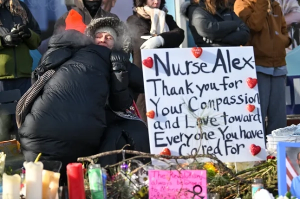 epaselect epa12681007 Жінку втішають біля імпровізованого меморіалу на честь Алекса Претті на півдні Міннеаполіса, штат Міннесота, США, 25 січня 2026 року. 37-річна Претті, медсестра відділення інтенсивної терапії (ВІТ), була смертельно поранена агентами Прикордонної служби США 24 січня. Місцеві лідери засудили стрілянину та закликали до виведення федеральних військ, тоді як Міністерство внутрішньої безпеки стверджує, що агенти діяли в порядку самооборони під час боротьби з озброєною особою. EPA/CRAIG LASSIG