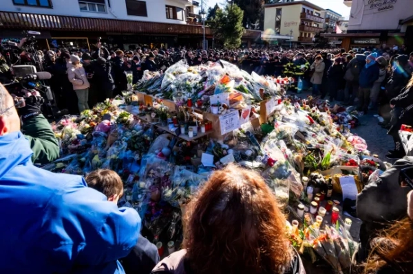 Люди зібралися навколо імпровізованого меморіалу, щоб віддати шану жертвам пожежі, поклавши квіти, свічки та висловивши свої побажання біля бару Constellation 4 січня 2026 року в Кран-Монтана на честь жертв пожежі, яка охопила місце проведення заходу на розкішному гірськолижному курорті в Альпах у новорічну ніч. Органи влади, які розслідують новорічну пожежу на швейцарському курорті Кран-Монтана, встановили особи 24 із 40 загиблих, включаючи 11 неповнолітніх та шістьох іноземних громадян, повідомила поліція 4 січня 2026 року. Також 119 осіб отримали поранення під час пожежі, більшість з них у важкому стані, згідно з останніми даними про жертви. (Фото MAXIME SCHMID / AFP via Getty Images)