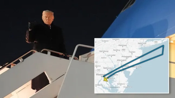 Дональд Трамп махає рукою біля літака з картою, на якій позначено його маршрут.