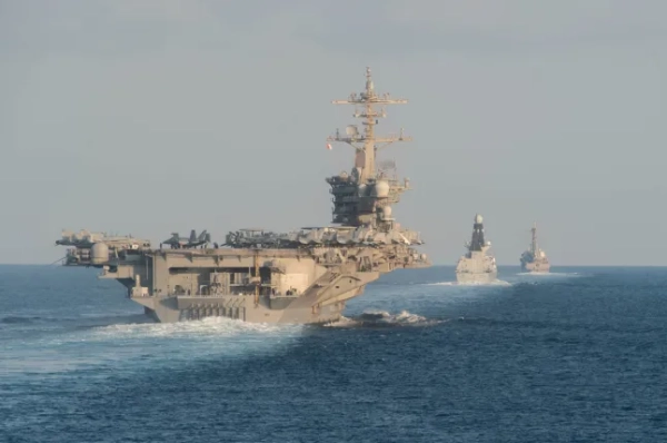 (ФАЙЛИ) Авіаносець USS Abraham Lincoln (L) проходить Ормузькою протокою 19 листопада 2019 року. Ударна група ВМС США на чолі з авіаносцем USS Abraham Lincoln розгорнулася у водах Близького Сходу, повідомили Сполучені Штати 26 січня 2026 року, тоді як Тегеран попередив про готовність завдати удару у відповідь на будь-яку американську атаку, розпочату у відповідь на придушення антиурядових протестів. (Фото Закарі Пірсона / ВМС США / AFP через Getty Images) / ОБМЕЖЕНО ДЛЯ РЕДАКЦІЙНОГО ВИКОРИСТАННЯ - ОБОВ'ЯЗКОВЕ ПОСИЛАННЯ
