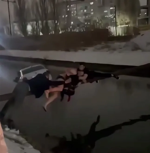 Троє чоловіків, що висіли на перекладині над каналом, рятують хлопчика та несуть його у безпечне місце