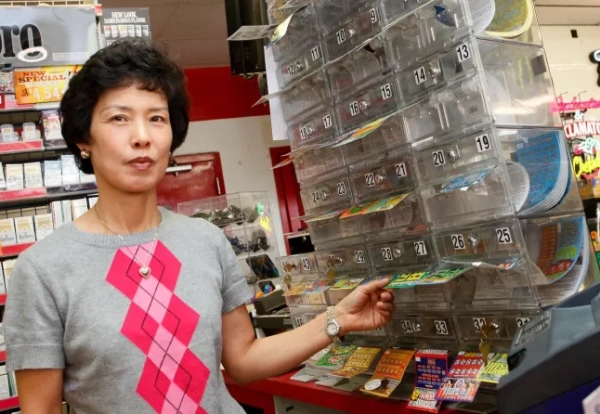 На цьому фото від 9 липня 2010 року Сун Бе, власниця магазину Times Market, стоїть поруч із лотерейними квитками у своєму магазині в Бішопі, штат Техас. Уродженка Бішопа Джоан Гінтер, яка зараз живе в Лас-Вегасі, минулого місяця виграла 10 мільйонів доларів на лотерейному квитку вартістю 50 доларів. Вона виграла чотири джекпоти Техаської лотереї на загальну суму 21 мільйон доларів, а два останні виграшні квитки були придбані в магазині Бе. (AP Photo/Steve Nurenberg)