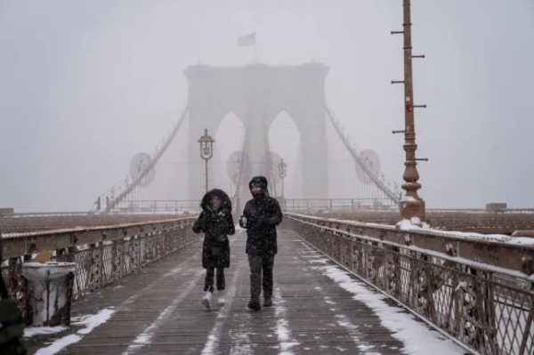 НЬЮ-ЙОРК, НЬЮ-ЙОРК – 25 СІЧНЯ: Двоє людей перетинають Бруклінський міст 25 січня 2026 року в районі Бруклін у Нью-Йорку. Потужний зимовий шторм приносить морози, лід та сніг мільйонам американців по всій країні. (Фото Роберта Нікельсберга/Getty Images)