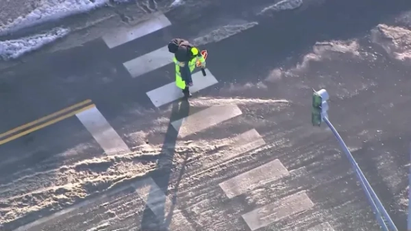 Аерофотознімок чоловічка-льодяника, який несе дитину та переходить дорогу, щоб забезпечити її безпеку.