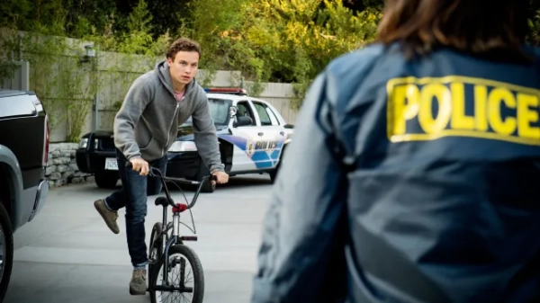 Фінн Коул у сцені з мультфільму «Царство тварин» їде на велосипеді, дивлячись на жінку-поліцейську, обличчя якої не видно.