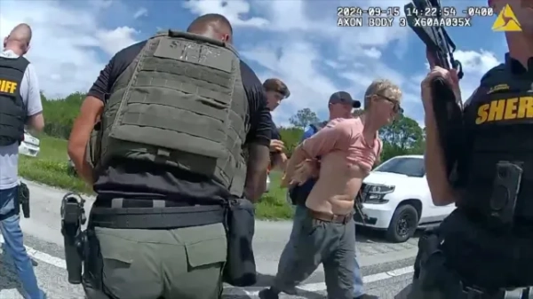 Обов'язкове джерело: Фото EyePress News/Shutterstock (14725262b) Знімок екрана з нещодавно опублікованих відео з нагрудної камери, знятих у понеділок, 16 вересня 2024 року, показує, що правоохоронні органи заарештували чоловіка у зв'язку з ймовірною спробою замаху на колишнього президента Дональда Трампа помічниками шерифа на шосе у Флориді. На відео, опублікованому офісом шерифа округу Мартін у понеділок, видно, як 58-річного Раяна Веслі Раута затримали без інцидентів у неділю, коли він їхав на північ по I-95. Арешт стався після того, як агенти Секретної служби вступили в бій з підозрюваним, який направив потужну гвинтівку в кущі поблизу поля для гольфу у Флориді, де Трамп грав у гольф, за кілька сотень ярдів. Раут залишив на місці події штурмову гвинтівку типу АК-47 та інші предмети. Інцидент стався майже рівно через два місяці після стрілянини на мітингу Трампа в Батлері, штат Пенсільванія, в результаті якої кандидат від республіканців отримав легкі травми, а в натовпі загинув чоловік. (Роздатковий матеріал офісу шерифа округу Мартін через EYEPRESS) Фото підозрюваного у стрільбі на Трампа, Палм-Біч, Флорида - 18 вересня 2024 року