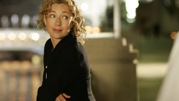 Алекс Кінгстон схилилася над мостом у відділенні невідкладної допомоги, одягнена в чорну куртку