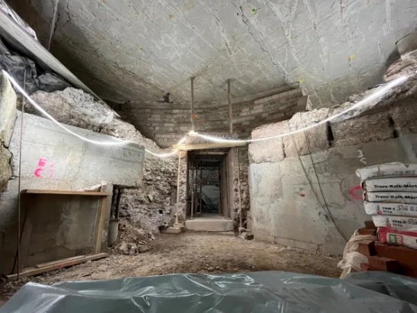 МАРК ВОРГАН Археологи, які працюють під історичним центром Кельна, виявили надзвичайно добре збережені римські залишки, зокрема рідкісну святиню домашніх богів, знайдену вперше в Північній Європі. За словами міських чиновників, знахідку було зроблено під час розкопок, пов'язаних з новим підземним маршрутом для відвідувачів у Єврейському музеї MiQua ??? LVR в Археологічному кварталі Кельна. Найбільш вражаючим відкриттям є ларарій – домашнє святилище, присвячене ларам, божествам-захисникам дому, – знайдене в колишньому римському преторії, палаці губернатора, який колись символізував імператорську владу в провінції Нижня Германія. Ларії були широко поширені в римських будинках по всьому Середземномор'ю. Цей, що датується II століттям, є унікальним на північ від Альп, а аналогічні приклади раніше знаходили лише в римських містах, похованих внаслідок вивержень вулканів, таких як Помпеї. Команда дослідників, яка брала участь у розкопках, каже, що кельнська знахідка майже безпрецедентна: сліди оригінального настінного розпису досі видно всередині вівтарної ніші. Невеликі отвори від цвяхів над і поруч із нішею свідчать про те, що колись святиню прикрашали гірлянди. Під ним чітка лінія розриву позначає місце, де спочатку був встановлений вівтарний стіл. Цю кам'яну плиту також було виявлено під час розкопок, і очікується, що її буде відновлено у початковому положенні. Відкриття були зроблені під час робіт, що проводилися містом Кельн у рамках підготовки до підземної екскурсії музею. Оскільки ділянки нового маршруту опускаються на незвичайну глибину, археологи змогли ідентифікувати споруди, які зазвичай втрачаються, будучи зруйнованими пізнішими будівельними роботами. У цьому випадку останки збереглися, оскільки вони вже були поховані в римські часи. Їхнє розташування на та під колишнім схилом річки Рейн означало, що вони були запечатані валами на початку античності, захищаючи їх від пізніших пошкоджень. Серед інших значущих знахідок - фундамент апсиди, що належить до великої багатонефної римської базиліки, що датується IV століттям. Її товщина досягала чотирьох метрів, і спочатку вважалося, що вона була зроблена з римського литого бетону, відомого як opus caementicium. Детальне дослідження виявило замість цього шарувату конструкцію з туфу, базальту та вапняку, скріплену надзвичайно міцним розчином з цегли та гравію. До розкопок споруда виглядала на площі ратуші Кельна лише як невелике заглиблення. Зараз вона вперше доступна для відвідувачів. Археологи також виявили сходи кінця I століття, які були виявлені лише під час поточних робіт. Сходи колись з'єднували низовину поблизу Рейну з вищою місцевістю, пов'язаною з раннім преторієм. Точна точка, де закінчувалися сходи, залишається невідомою. Сходи рідко зберігаються в археологічних даних Кельна, оскільки більшість римських будівель збереглися лише на рівні фундаменту. Фахівці кажуть, що цей екземпляр зберігся завдяки сприятливим топографічним умовам, коли ранні римські споруди були поховані під час засипання ще в римський період. Очікується, що знахідки стануть центральною частиною підземної екскурсії, коли музей MiQua відкриється для публіки. Особливості: Прорив в апсиді. Де: Кельн, Німеччина Коли: 24 лютого 2026 р. Авторство: Місто Кельн/Римсько-германський музей, Міхаель Віен/Зображення обкладинки **З усіх питань використання та запитів звертайтеся за адресою info@cover-images.com - +44 (0)20 3397 3000 ЛИШЕ ДЛЯ РЕДАКЦІЙНОГО ВИКОРИСТАННЯ. МАТЕРІАЛИ ДЛЯ ВИКОРИСТАННЯ ЛИШЕ РАЗОМ З РЕДАКЦІЙНОЮ СТАТТЮ. ВИКОРИСТАННЯ ЦИХ МАТЕРІАЛІВ ДЛЯ РЕКЛАМИ, МАРКЕТИНГУ АБО БУДЬ-ЯКИХ ІНШИХ КОМЕРЦІЙНИХ ЦІЛЕЙ СУВОРО ЗАБОРОНЕНО. АВТОРСЬКЕ ПРАВО НА МАТЕРІАЛИ ЗАЛИШАЄТЬСЯ У ЗАЯВЛЕНОГО ПОСТАЧАЛЬНИКА.**