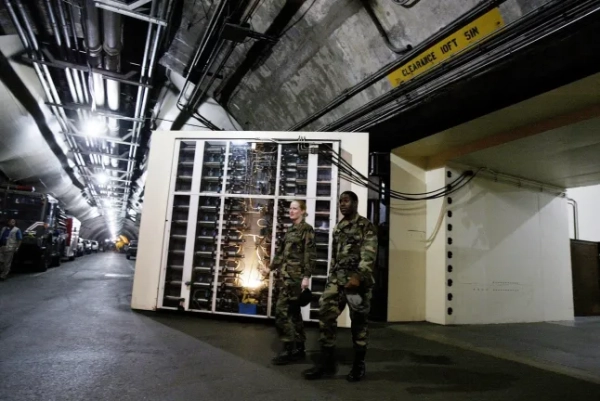 КОЛОРАДО-СПРІНГС, КОЛОРАДО – 11 ТРАВНЯ: Біля внутрішнього входу до штаб-квартири NORAD у гірському комплексі Шайєнн двоє військовослужбовців виходять з адміністративної зони 11 травня 2004 року в Колорадо-Спрінгс, штат Колорадо. Побудоване під час Холодної війни в 1958 році, NORAD (Північноамериканське аерокосмічне командування) відповідало за зовнішню повітряну, ракетну та космічну оборону. З 11 вересня 2001 року воно щодня спостерігає за 7000 літаками в межах США. NORAD контролює схему польотів кожного літака, включаючи непередбачені випадки польотів та посадок президента США. NORAD координує свої дії з цивільною владою та співпрацює з Пентагоном, федеральною, державною та місцевою владою. Канадські військові становлять 10-15 відсотків від 326 осіб загальної кількості персоналу NORAD. NORAD співпрацює з Міністерством внутрішньої безпеки (DHS), але не є частиною DHS. Персонал працює на висоті 7000 футів всередині гранітної гори. Двоє 25-тонних дверей безпеки закривають внутрішні офіси від будь-якого типу атаки. NORAD має самодостатню систему виживання з незалежним постачанням води та повітря. (Фото Роберта Нікельсберга/Getty Images)