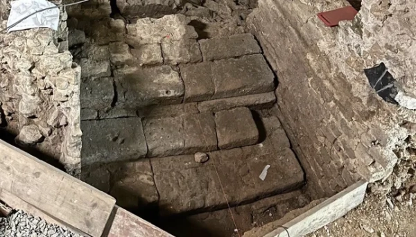 МАРК ВОРГАН Археологи, які працюють під історичним центром Кельна, виявили надзвичайно добре збережені римські залишки, зокрема рідкісну святиню домашніх богів, знайдену вперше в Північній Європі. За словами міських чиновників, знахідку було зроблено під час розкопок, пов'язаних з новим підземним маршрутом для відвідувачів у Єврейському музеї MiQua ??? LVR в Археологічному кварталі Кельна. Найбільш вражаючим відкриттям є ларарій – домашнє святилище, присвячене ларам, божествам-захисникам дому, – знайдене в колишньому римському преторії, палаці губернатора, який колись символізував імператорську владу в провінції Нижня Германія. Ларії були широко поширені в римських будинках по всьому Середземномор'ю. Цей, що датується II століттям, є унікальним на північ від Альп, а аналогічні приклади раніше знаходили лише в римських містах, похованих внаслідок вивержень вулканів, таких як Помпеї. Команда дослідників, яка брала участь у розкопках, каже, що кельнська знахідка майже безпрецедентна: сліди оригінального настінного розпису досі видно всередині вівтарної ніші. Невеликі отвори від цвяхів над і поруч із нішею свідчать про те, що колись святиню прикрашали гірлянди. Під ним чітка лінія розриву позначає місце, де спочатку був встановлений вівтарний стіл. Цю кам'яну плиту також було виявлено під час розкопок, і очікується, що її буде відновлено у початковому положенні. Відкриття були зроблені під час робіт, що проводилися містом Кельн у рамках підготовки до підземної екскурсії музею. Оскільки ділянки нового маршруту опускаються на незвичайну глибину, археологи змогли ідентифікувати споруди, які зазвичай втрачаються, будучи зруйнованими пізнішими будівельними роботами. У цьому випадку останки збереглися, оскільки вони вже були поховані в римські часи. Їхнє розташування на та під колишнім схилом річки Рейн означало, що вони були запечатані валами на початку античності, захищаючи їх від пізніших пошкоджень. Серед інших значущих знахідок - фундамент апсиди, що належить до великої багатонефної римської базиліки, що датується IV століттям. Її товщина досягала чотирьох метрів, і спочатку вважалося, що вона була зроблена з римського литого бетону, відомого як opus caementicium. Детальне дослідження виявило замість цього шарувату конструкцію з туфу, базальту та вапняку, скріплену надзвичайно міцним розчином з цегли та гравію. До розкопок споруда виглядала на площі ратуші Кельна лише як невелике заглиблення. Зараз вона вперше доступна для відвідувачів. Археологи також виявили сходи кінця I століття, які були виявлені лише під час поточних робіт. Сходи колись з'єднували низовину поблизу Рейну з вищою місцевістю, пов'язаною з раннім преторієм. Точна точка, де закінчувалися сходи, залишається невідомою. Сходи рідко зберігаються в археології Кельна, оскільки більшість римських будівель збереглися лише на рівні фундаменту. Фахівці кажуть, що цей екземпляр зберігся завдяки сприятливим топографічним умовам, коли ранні римські споруди були поховані під час засипання ще в римський період. Очікується, що знахідки стануть центральною частиною підземної екскурсії, коли музей MiQua відкриється для публіки. У ньому представлено: Фрагмент римських сходів I століття. Де: Кельн, Німеччина Коли: 24 лютого 2026 р. Авторство: Місто Кельн/Римсько-германський музей, Франциска Барц/Зображення обкладинки **З усіх питань використання та запитів звертайтеся за адресою info@cover-images.com - +44 (0)20 3397 3000 ЛИШЕ ДЛЯ РЕДАКЦІЙНОГО ВИКОРИСТАННЯ. МАТЕРІАЛИ ДЛЯ ВИКОРИСТАННЯ ЛИШЕ РАЗОМ З РЕДАКЦІЙНОЮ СТАТТЮ. ВИКОРИСТАННЯ ЦИХ МАТЕРІАЛІВ ДЛЯ РЕКЛАМИ, МАРКЕТИНГУ АБО БУДЬ-ЯКИХ ІНШИХ КОМЕРЦІЙНИХ ЦІЛЕЙ СУВОРО ЗАБОРОНЕНО. АВТОРСЬКЕ ПРАВО НА МАТЕРІАЛИ ЗАЛИШАЄТЬСЯ У ЗАЯВЛЕНОГО ПОСТАЧАЛЬНИКА.**