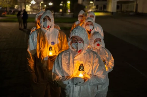Люди, одягнені в білі захисні костюми, несуть свічки під час поминальної служби, присвяченої пожежникам та робітникам, які загинули після Чорнобильської ядерної катастрофи 1986 року, напередодні її 40-ї річниці у Славутичі, Україна, субота, 25 квітня 2026 року. Чорнобиль – це українська назва міста. (Фото AP/Ден Башаков)