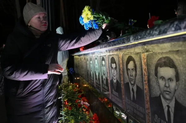 Жінка ставить свічку перед меморіалом жертвам Чорнобиля під час церемонії вшанування 40-ї річниці вибуху на Чорнобильській атомній електростанції, найгіршої цивільної ядерної катастрофи в історії, у місті Славутич 26 квітня 2026 року, на тлі російського вторгнення в Україну. (Фото Гені САВІЛОВОЇ / AFP via Getty Images)