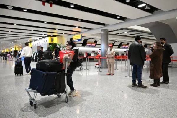 Пасажири збираються в закритій зоні реєстрації Emirates в аеропорту Хітроу в західному Лондоні 1 березня 2026 року, оскільки рейси серйозно порушені після ударів США та Ізраїлю по Ірану. Найбільші порушення світового повітряного транспорту з часів пандемії Covid продовжилися в неділю, внаслідок чого постраждали тисячі рейсів, а завантажені близькосхідні вузли, включаючи Дубай та Доху, були закриті, оскільки Іран завдав удару після американо-ізраїльських ударів. (Фото JASTIN TALLIS / AFP via Getty Images)