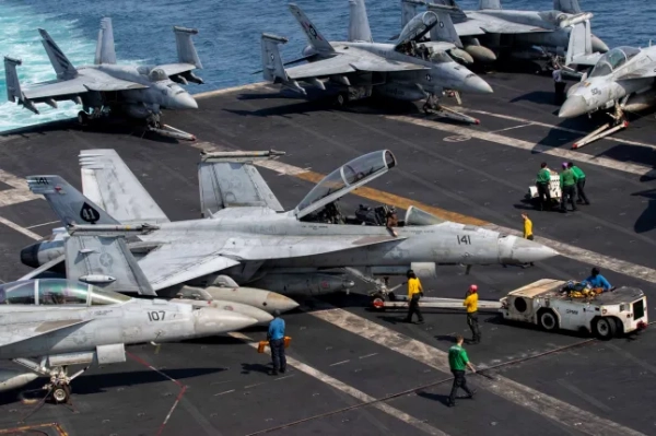 На цій фотографії з роздаткового матеріалу ВМС США, опублікованій 18 березня 2026 року Центральним командуванням США зі зв'язків з громадськістю, зображено американських моряків, які рулять літаком F/A-18F Super Hornet, прикріпленим до 41-ї ескадрильї ударних винищувачів (VFA), на палубі польоту на борту авіаносця класу Nimitz USS Abraham Lincoln (CVN 72) на підтримку операції 