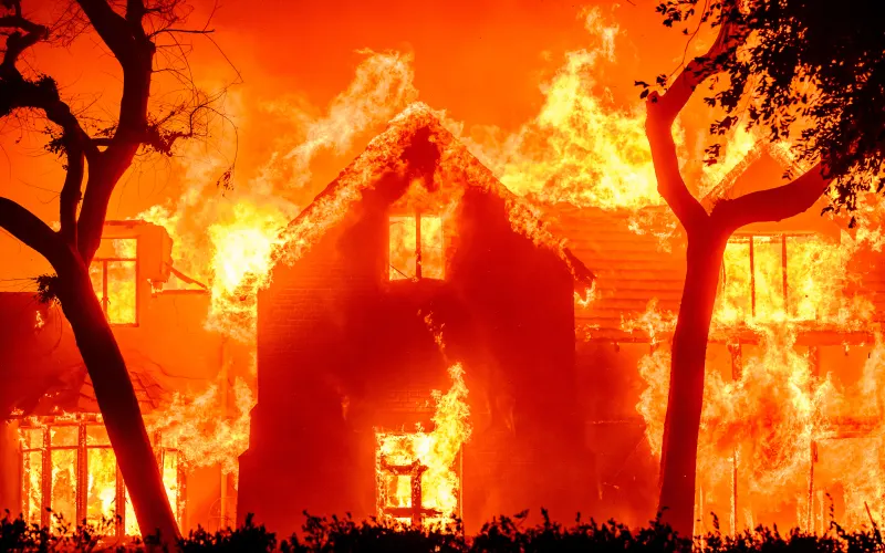 (FILES) A home is engulfed in flames during the Eaton fire in the Altadena area of Los Angeles County, California on January 8, 2025. One of the deadly 2025 fires that ravaged Los Angeles was caused when sparks from an idle transmission tower owned by a local power company ignited dry vegetation, fire officials said in a report released on on August 4, 2026. The report, released after an 18-month investigation, confirms suspicions that utility Southern California Edison (SCE) was responsible for the Eaton Fire that killed 19 people and damaged thousands of homes and other buildings in January 2025. (Photo by JOSH EDELSON / AFP)