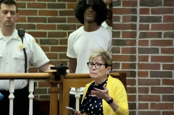 Arjun Aravind listens as his lawyer Debra DeWitt speaks during his arraignment at Concord District Court in Concord, Mass., on Thursday, Aug. 13, 2026, for the murders of his mother and younger brother at their home in Acton, Mass. (Lane Turner/The Boston Globe via AP)