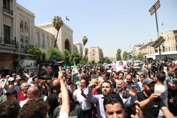 DAMASCUS, SYRIA - AUGUST 11: Syrians gather around the Palace of Justice to celebrate a court's death sentences against ousted leader Bashar al-Assad, his brother Maher al-Assad and his cousin Atef Najib, carrying photographs of people killed by the Assad regime, in the capital Damascus, Syria, on August 11, 2026. (Photo by Izz Aldien Alqasem/Anadolu via Getty Images)