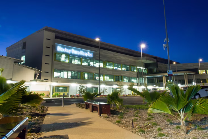 Багатоповерхова будівля з неоновою вивіскою «Mackay Base Hospital».