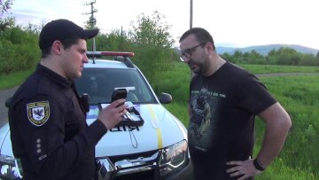 Поліцейський перевіряє водія за дпомогою алкотестера