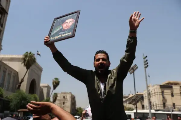 DAMASCUS, SYRIA - AUGUST 11: Syrians gather around the Palace of Justice to celebrate a court's death sentences against ousted leader Bashar al-Assad, his brother Maher al-Assad and his cousin Atef Najib, carrying photographs of people killed by the Assad regime, in the capital Damascus, Syria, on August 11, 2026. (Photo by Izz Aldien Alqasem/Anadolu via Getty Images)