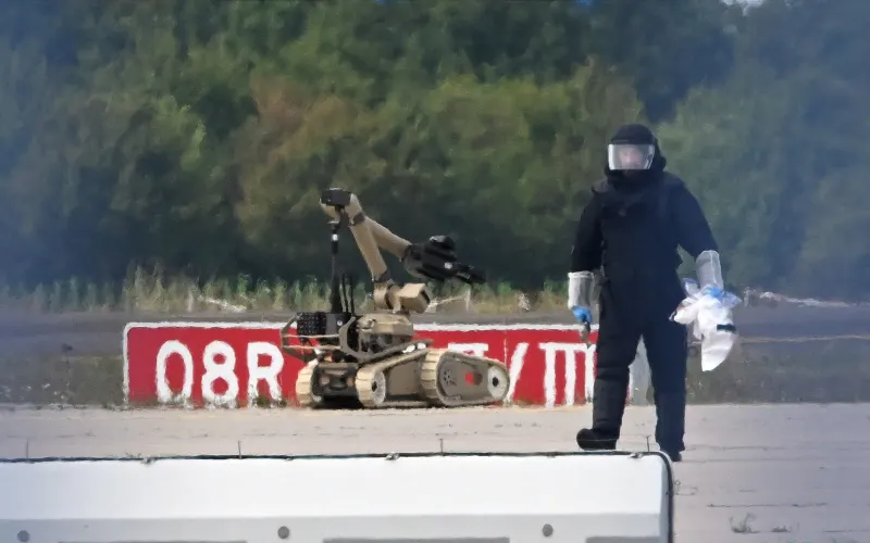 Працівник криміналістичної експертизи працює біля робота-сапера, біля українського вантажного літака в аеропорту Лейпциг-Галле в Шкойдіці, східна Німеччина, 5 серпня 2026 року, після того, як поблизу літака було знайдено дрон, начинений вибухівкою, а інший літак зіткнувся з невідомим літаючим об’єктом у повітрі перед безпечною посадкою.