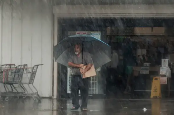 A resident carries supplies during Hurricane Lala in Hawaiian Ocean View, Hawaii, Saturday, Aug. 15, 2026. (Stephen Lam/San Francisco Chronicle via AP)