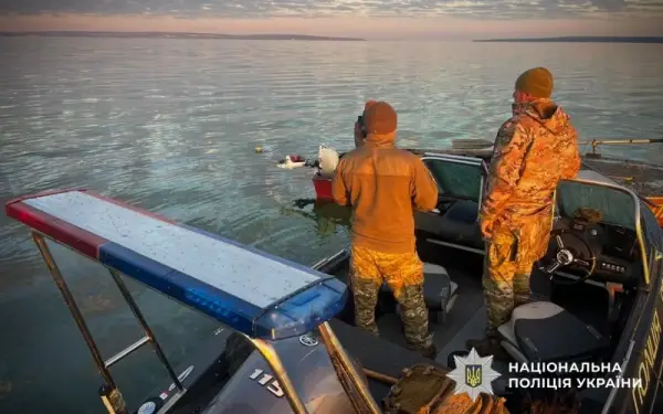 Двоє чоловіків у формі стоять на катері спиною до камери
